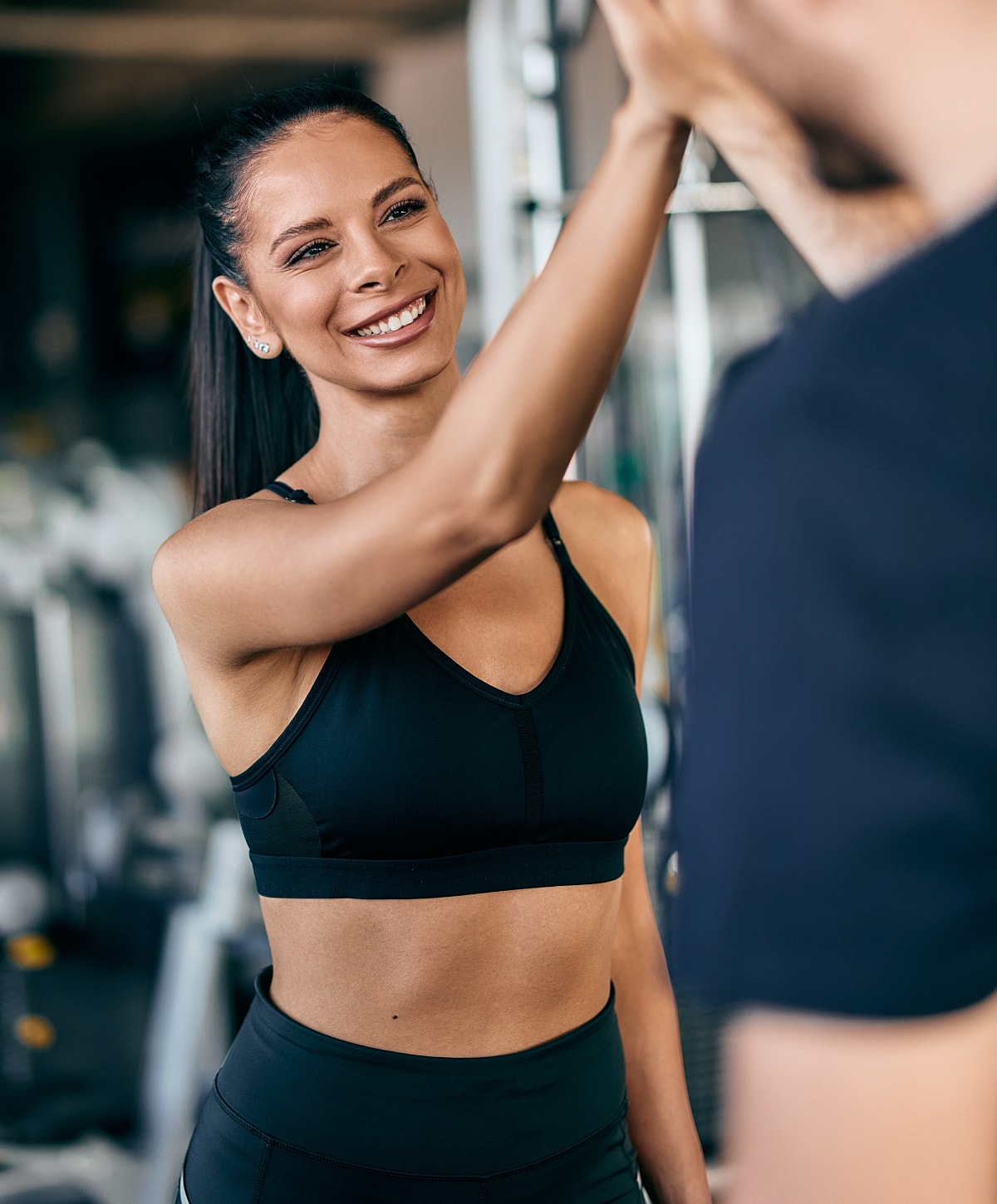Smiling woman high-fiving in gym setting.