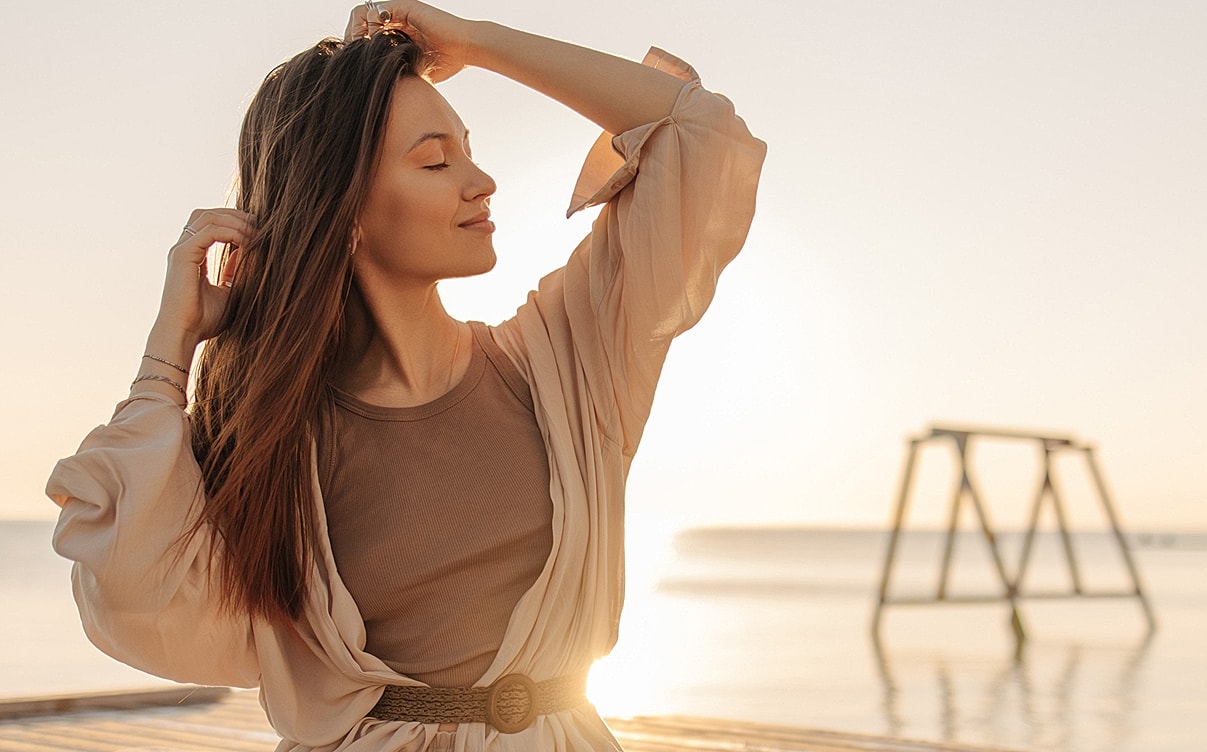 Woman enjoying sunset by calm water.