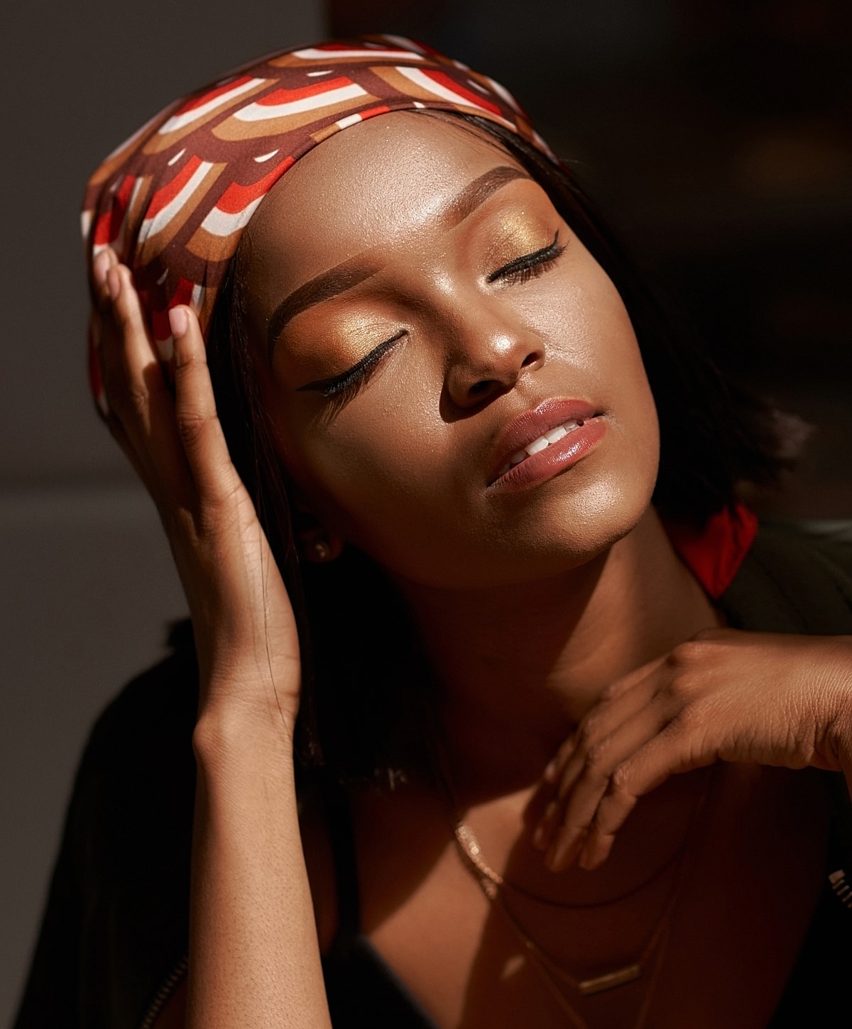 Woman with closed eyes and colorful headscarf.