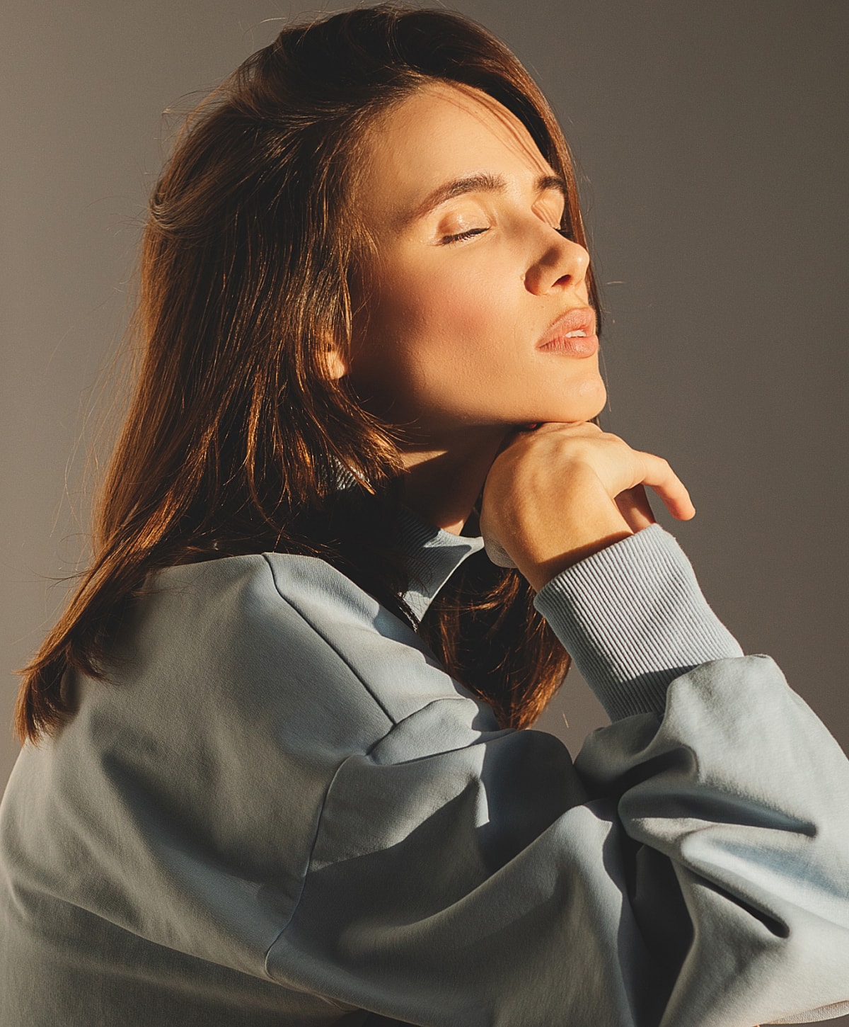 Woman with closed eyes in soft lighting.