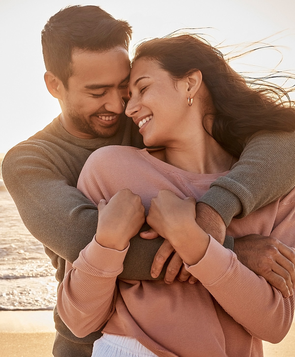 Couple embracing on the beach at sunset.